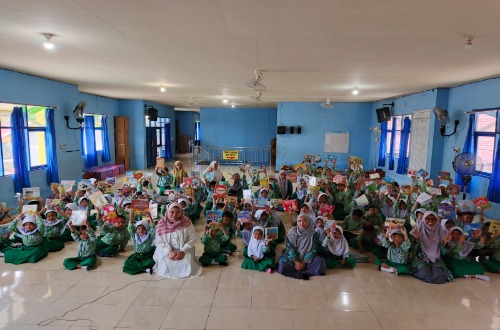 Anak-anak TK bersama guru mereka duduk di aula sekolah sambil memegang buku cerita, mengikuti kegiatan storytelling dari Dinas Perpustakaan Kotabaru.