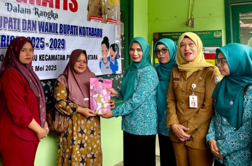 Seorang akseptor KB menerima bingkisan dari Wakil Ketua I TP. PKK Kotabaru didampingi pejabat dan kader PKK.