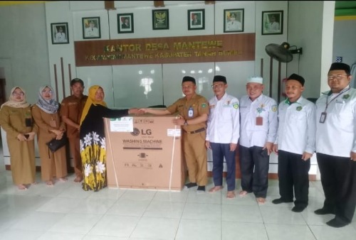 Baznas Tanah Bumbu menyerahkan bantuan mesin cuci kepada korban kebakaran di Kantor Desa Mantewe.