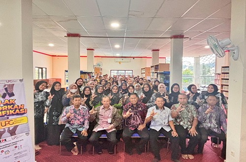 Peserta Bimtek Strategi Pengembangan Perpustakaan Berbasis Inklusi Sosial di Aula Dispersip Kotabaru, berfoto bersama sambil menunjukkan simbol literasi.