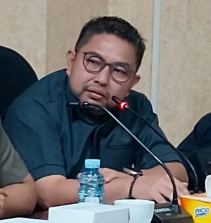 H.M. Syaripuddin, S.E., M.A.P., atau Bang Dinn, Anggota DPRD Kalimantan Selatan, sedang berbicara dalam rapat menggunakan mikrofon.