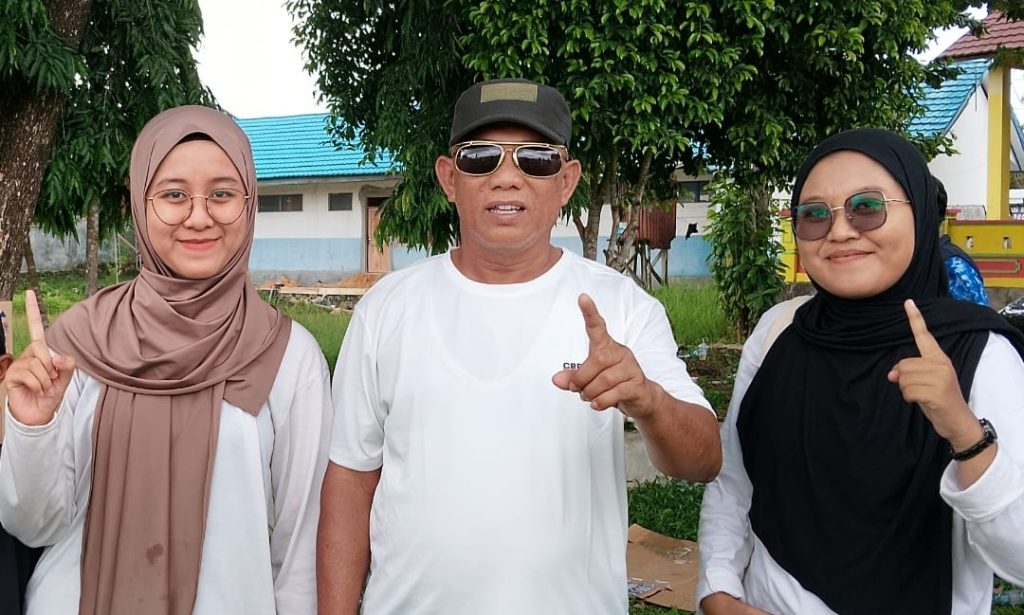 Mardhatillah berkerudung coklat di sisi kiri, Bupati Kotabaru di tengah, dan kakaknya berkerudung hitam di sisi kanan.