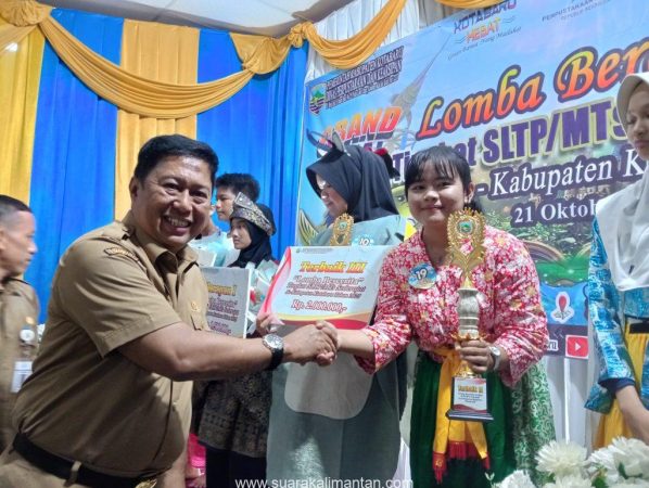 Kepala Dinas Perpustakaan dan Kearsipan Kabupaten Kotabaru menyerahkan piala dan piagam penghargaan kepada salah satu pemenang Lomba Bercerita Tingkat SMP/MTs se-Kabupaten Kotabaru Tahun 2025.