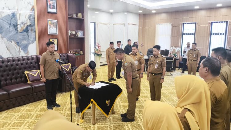 Bupati Kotabaru H. Muhammad Rusli menandatangani dokumen pelantikan pejabat di lingkungan Pemkab Kotabaru, disaksikan para ASN dan pejabat yang dilantik di ruang kerja bupati.