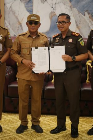 Bupati Kotabaru bersama Kepala Kejaksaan Negeri Kotabaru menunjukkan dokumen MoU kerja sama bidang hukum.